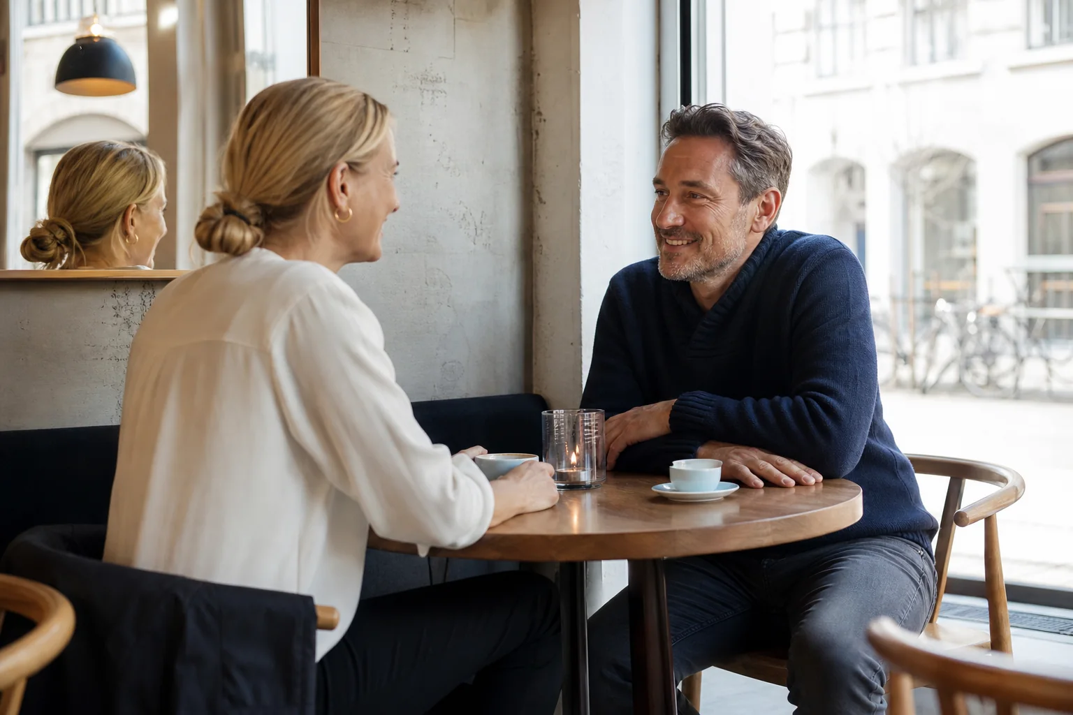 To voksne singler taler sammen over kaffe på en lys café